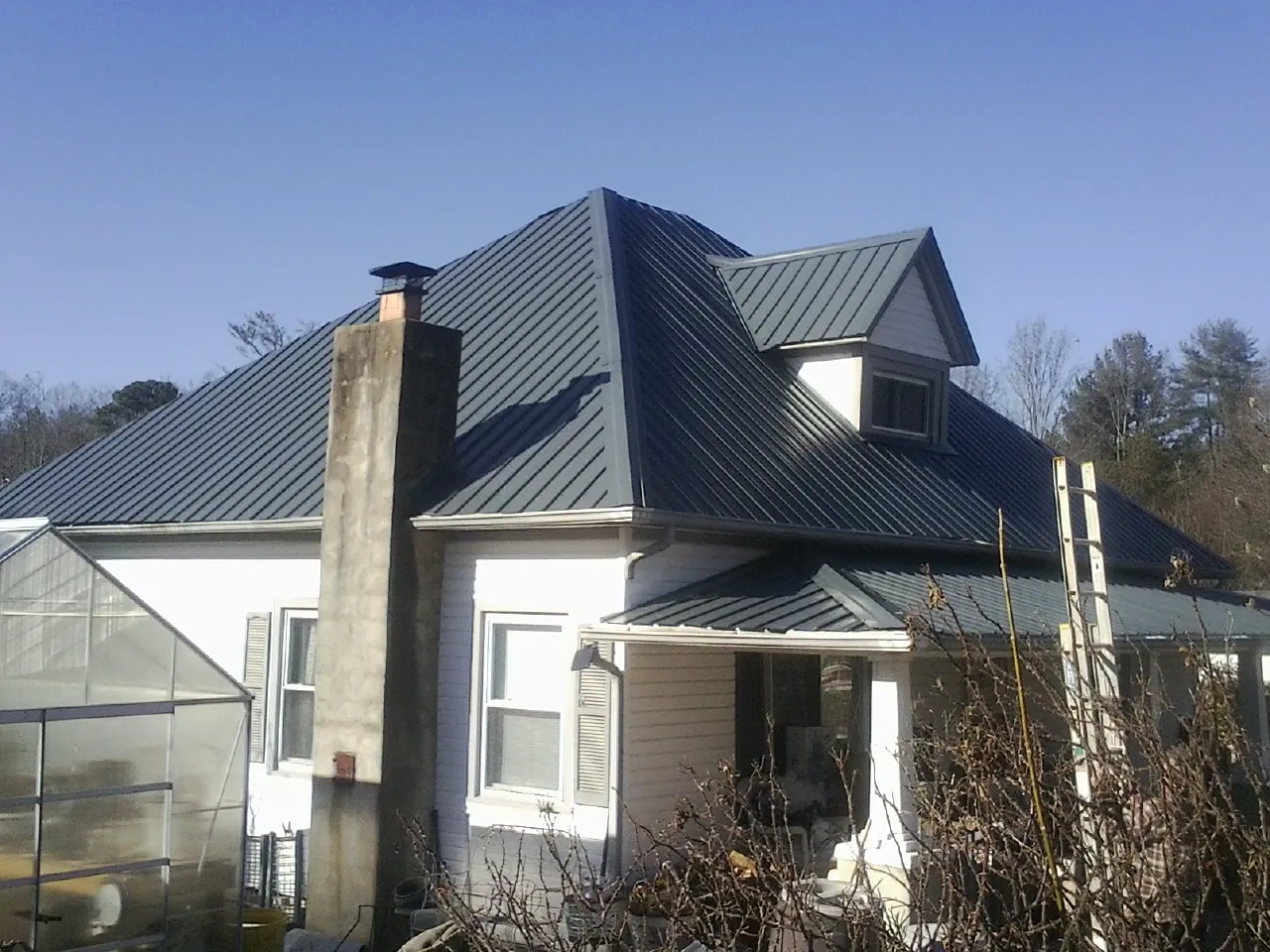 Dark blue standing seam metal roof on a white farmhouse with dormer — Slate & Tile Roof Repair by Roofing Brothers in Deridder