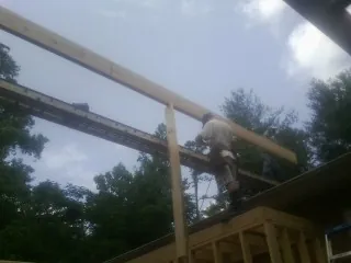 Carpenter setting a ridge beam over a new addition frame — Ice Dam Removal by Roofing Brothers in Deridder