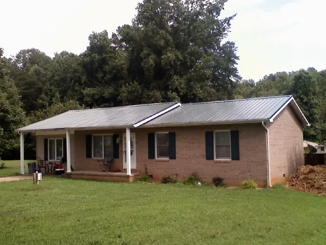 Gray metal roof on a brick ranch house with a side carport in Deridder