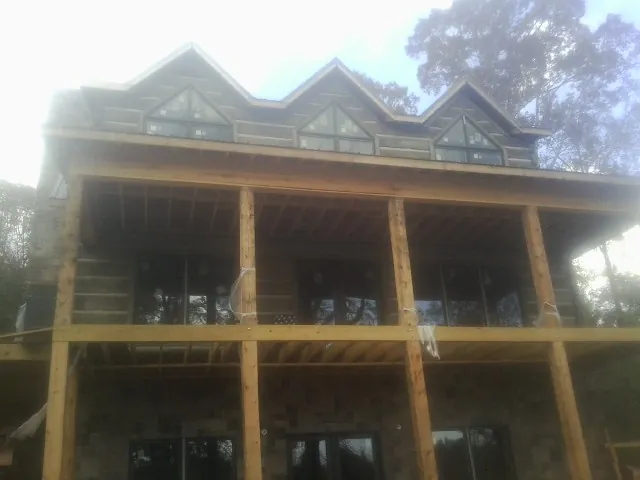 Dormers and porch framing on a large log home under construction — Roof Coating work by our crew in Deridder