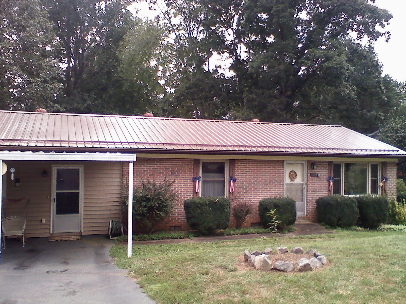 Bronze metal roof and carport on a brick ranch home — Roof Repair work by our crew in Deridder