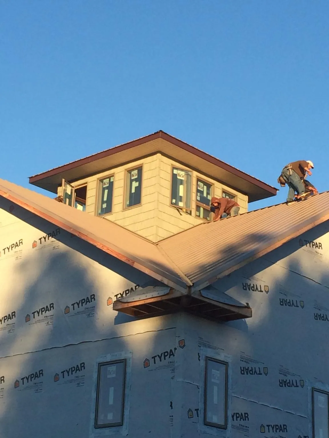 Roofers working around a rooftop cupola on a new metal roof at sunset — Roof Waterproofing in Deridder by Roofing Brothers